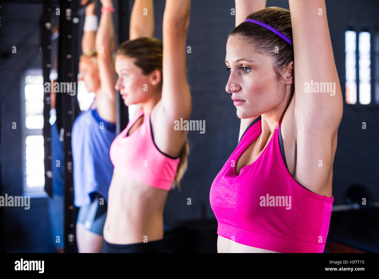 Woman doing chin-ups in gym Stock Photo