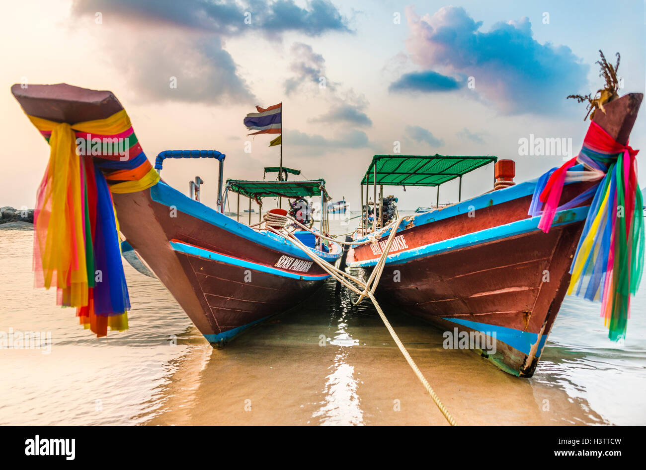 Moored colorful traditional long-tail boats on sandy beach, Ko Pha-ngan, Thailand Stock Photo