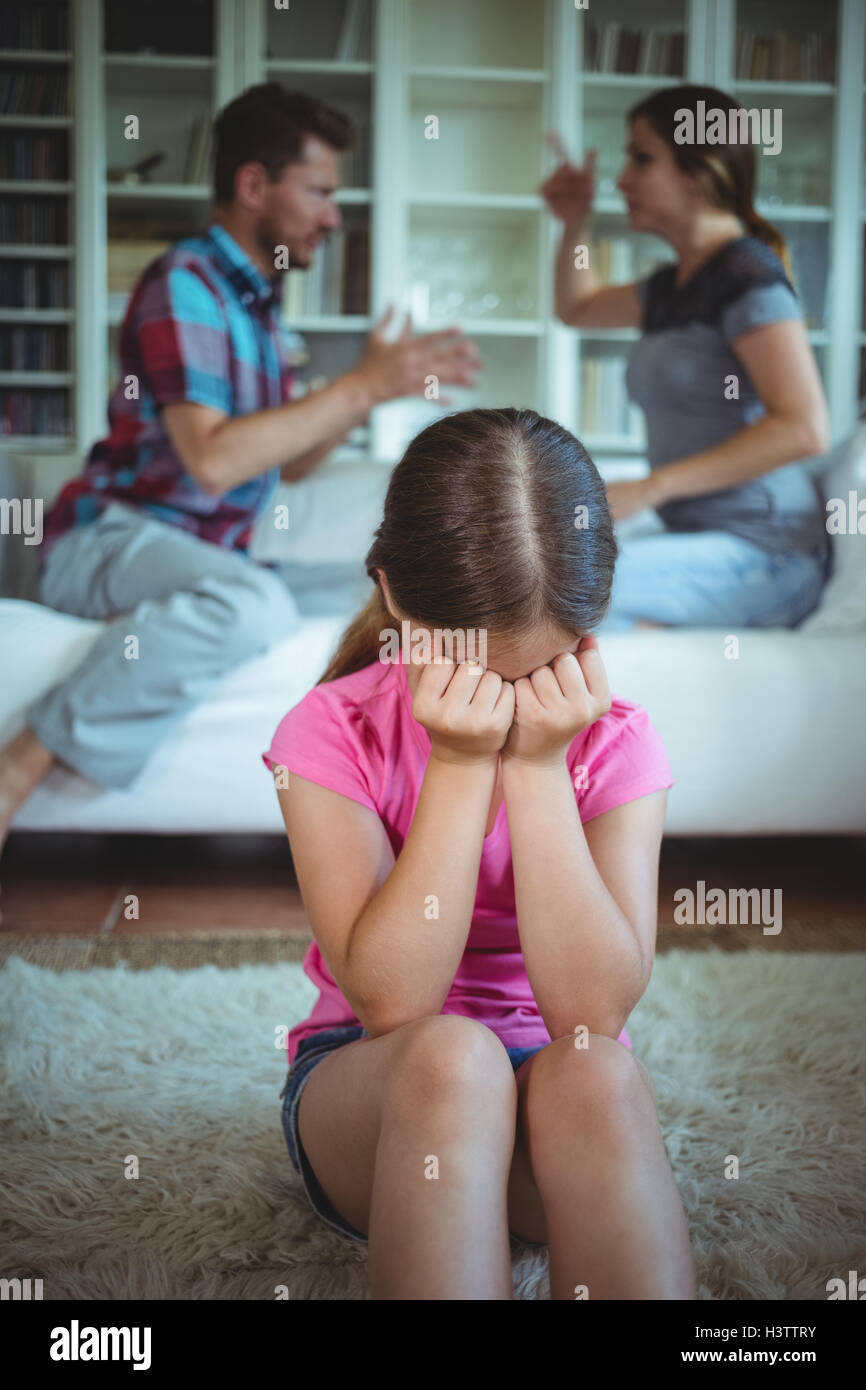 Sad girl crying while parents arguing in living room Stock Photo