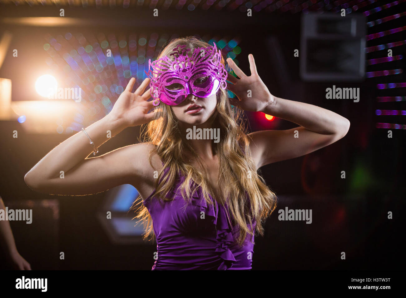 Woman with masquerade dancing on dance floor Stock Photo