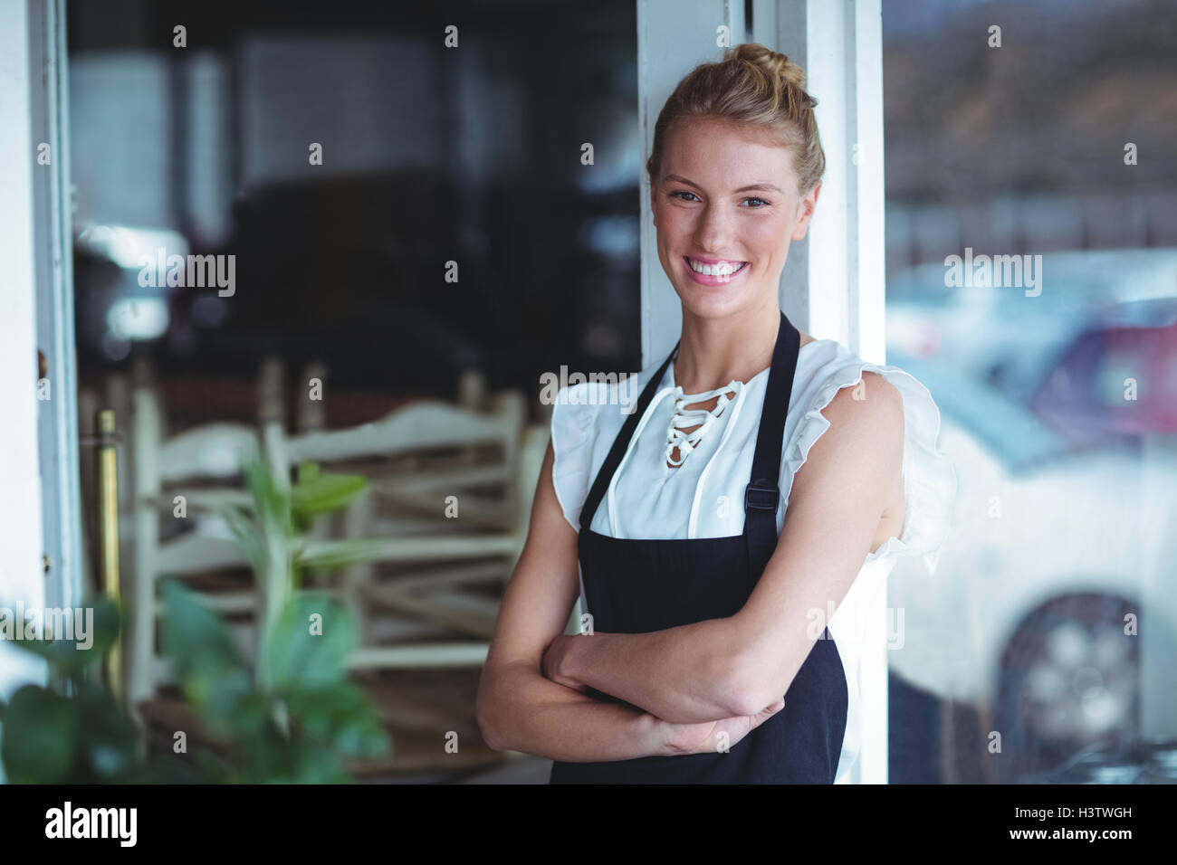 Portrait of smiling waitress standing with arms crossed Stock Photo - Alamy