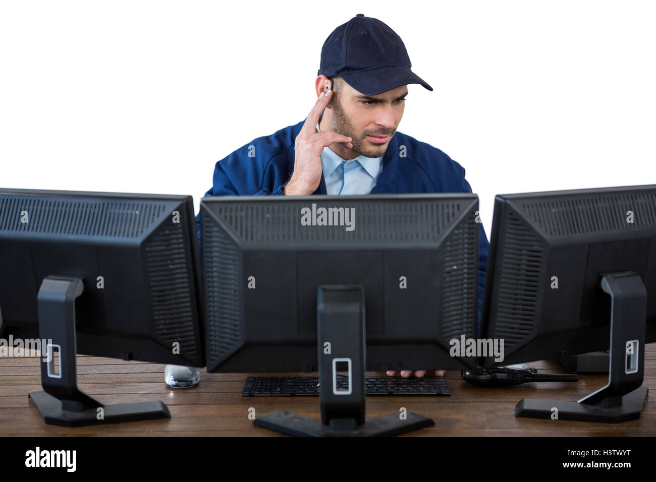 Security officer listening to earpiece while using computer Stock Photo