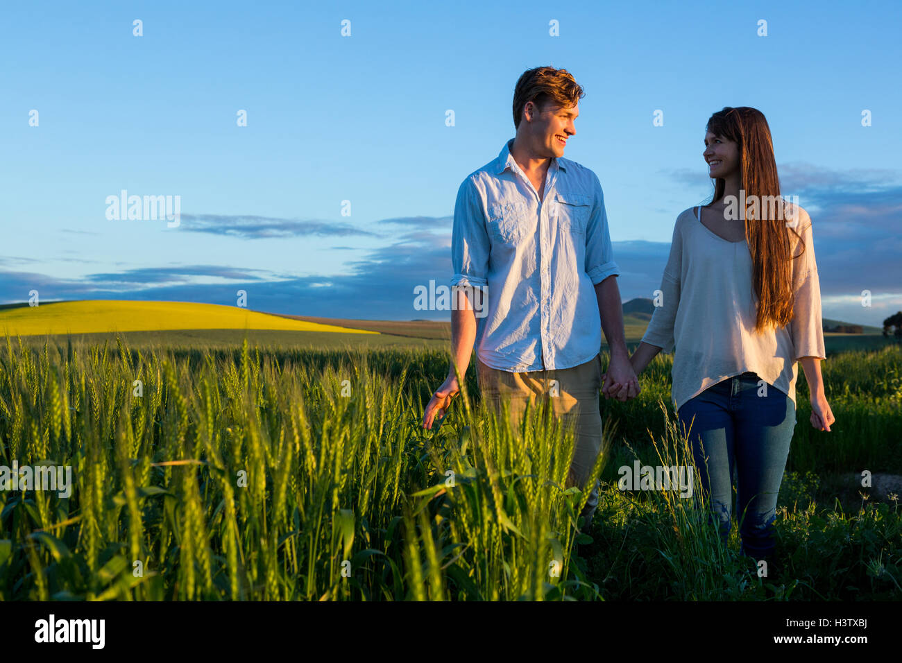 Couple holding hands in field Stock Photo - Alamy