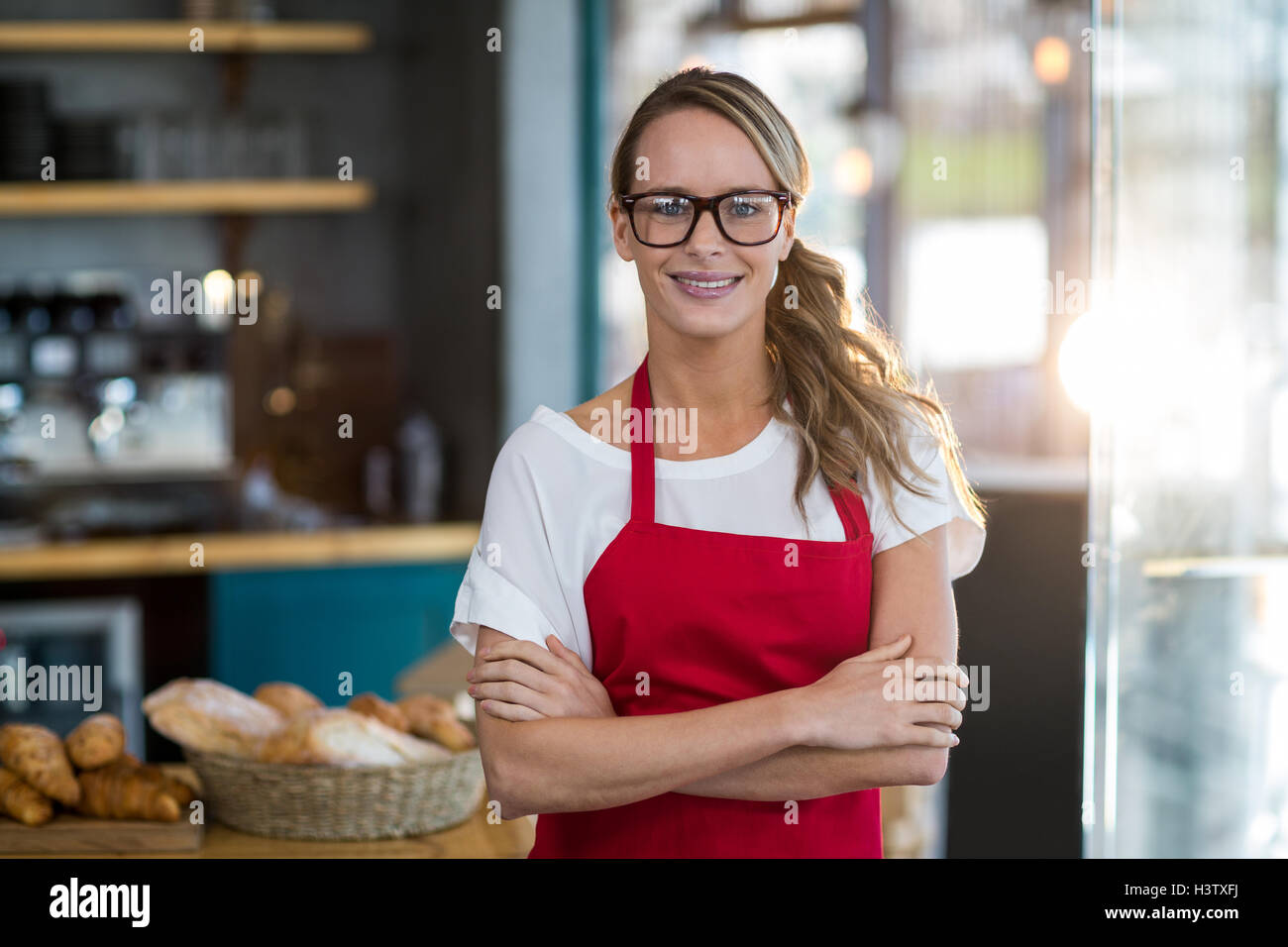 Portrait of smiling waitress standing with arms crossed Stock Photo - Alamy