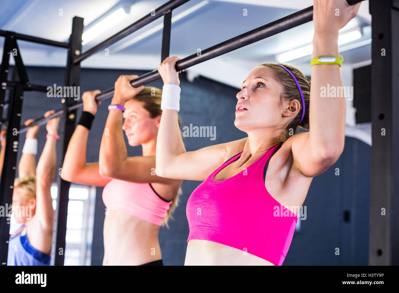 People doing chin-ups in gym Stock Photo