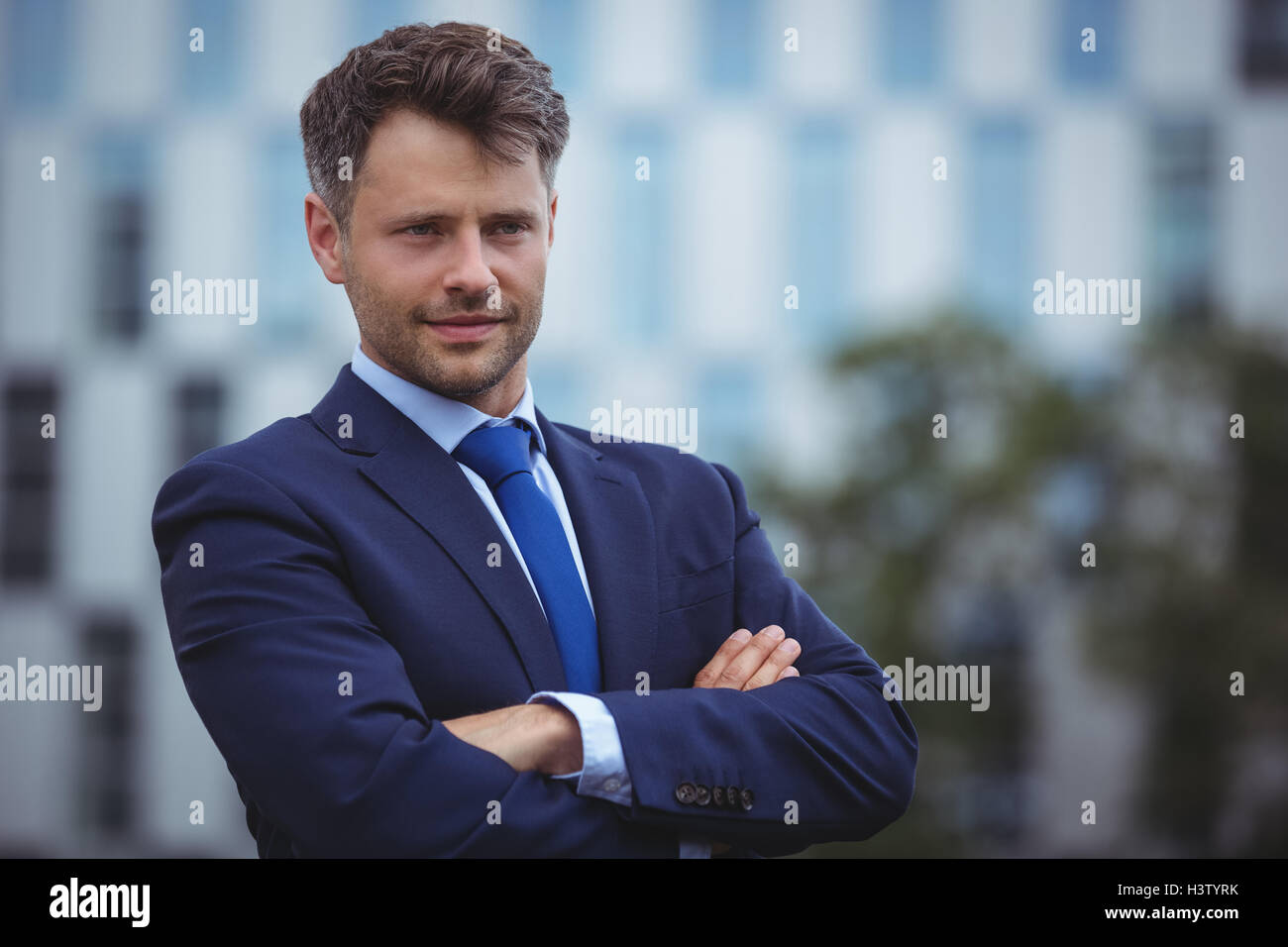 Handsome businessman standing with arms crossed Stock Photo - Alamy