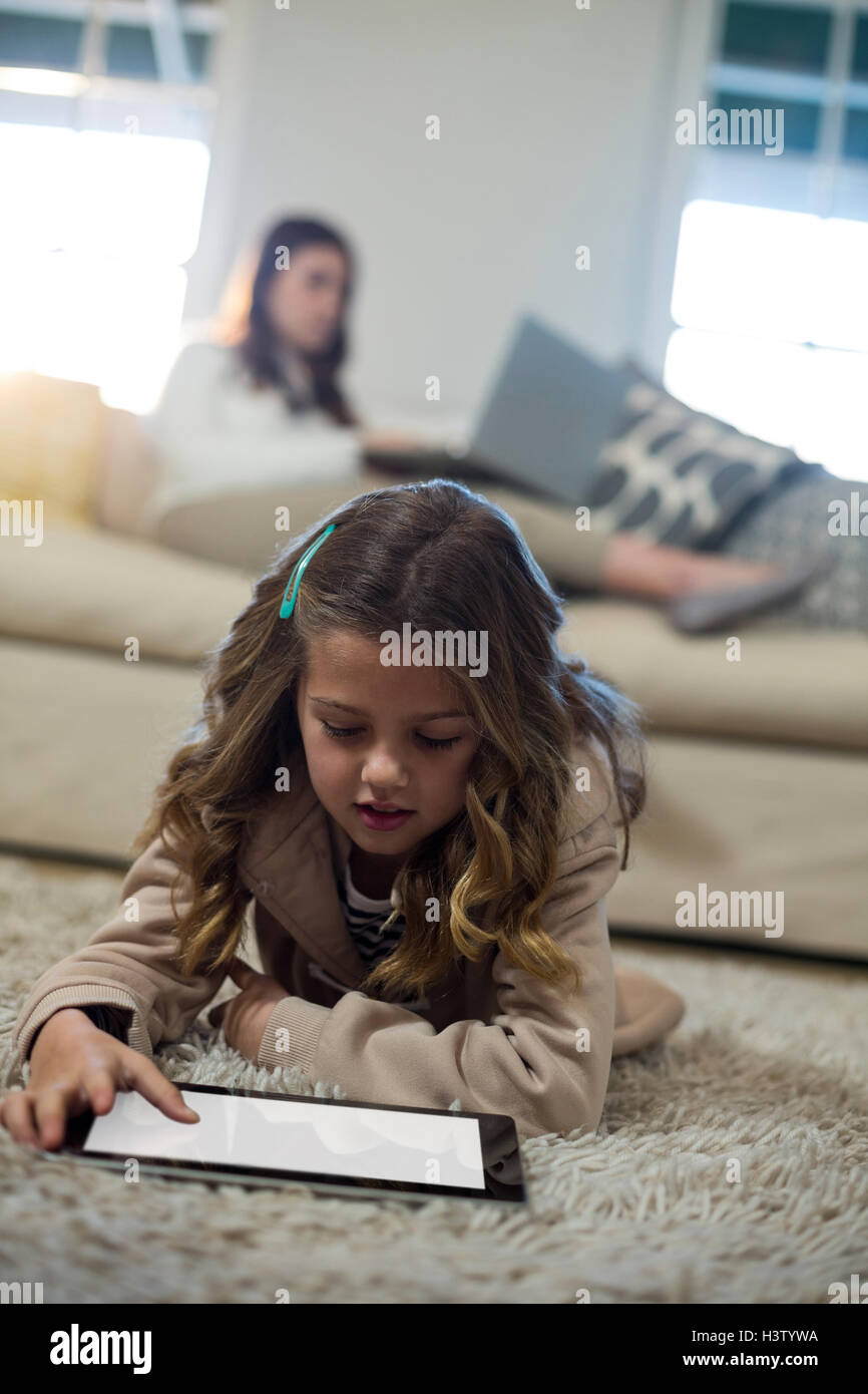 Girl using digital tablet while lying on the floor Stock Photo - Alamy