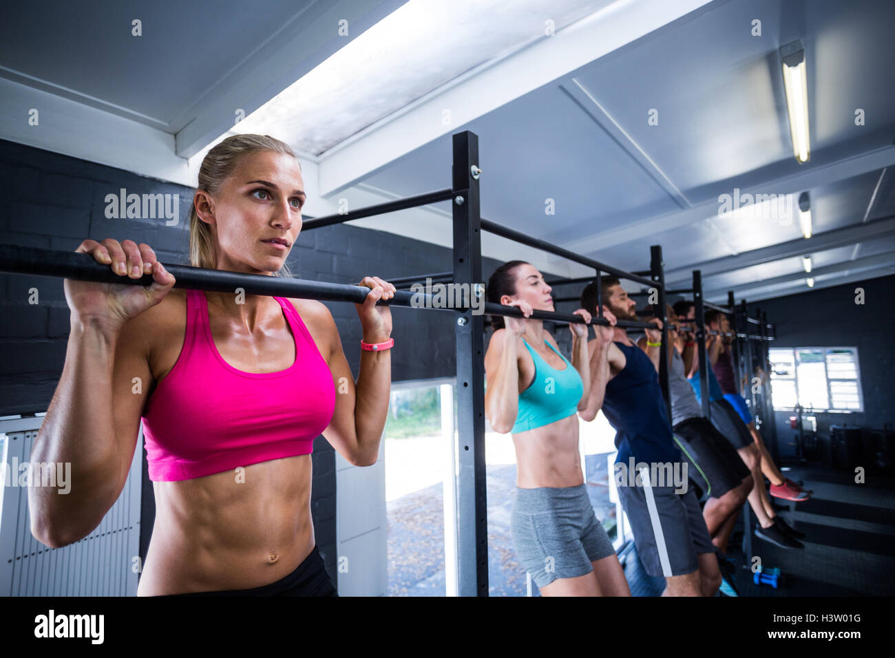 Athletes doing chin-ups in gym Stock Photo