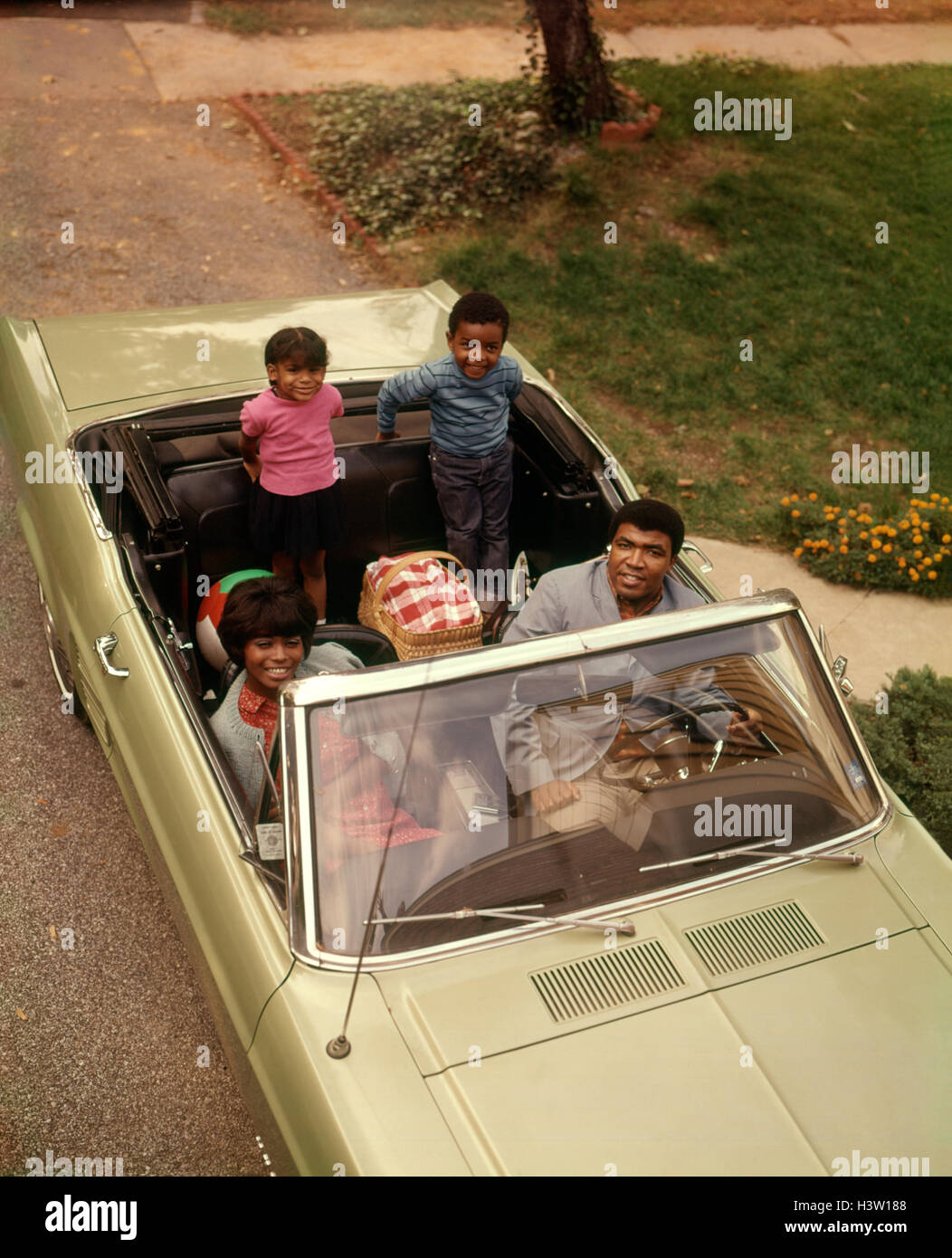 1970s AFRICAN AMERICAN FAMILY OF FOUR SEATED IN CONVERTIBLE CAR FATHER MOTHER SON DAUGHTER LOOKING AT CAMERA Stock Photo