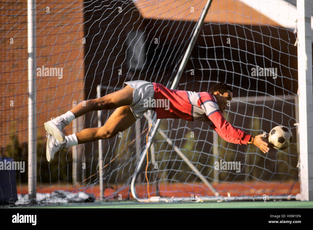 1980s SOCCER PLAYER GOALIE IN MIDAIR TRYING TO PREVENT A GOAL Stock