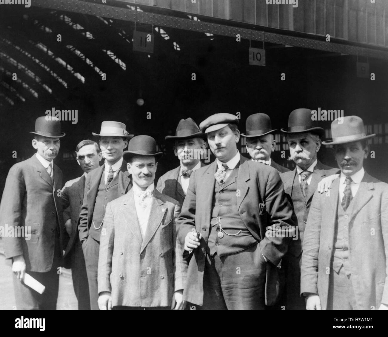 1900s GROUP OF MEN IN SUITS & HATS STANDING LOOKING AT CAMERA AT PENNSYLVANIA RAILROAD STATION IN PITTSBURGH PA USA Stock Photo