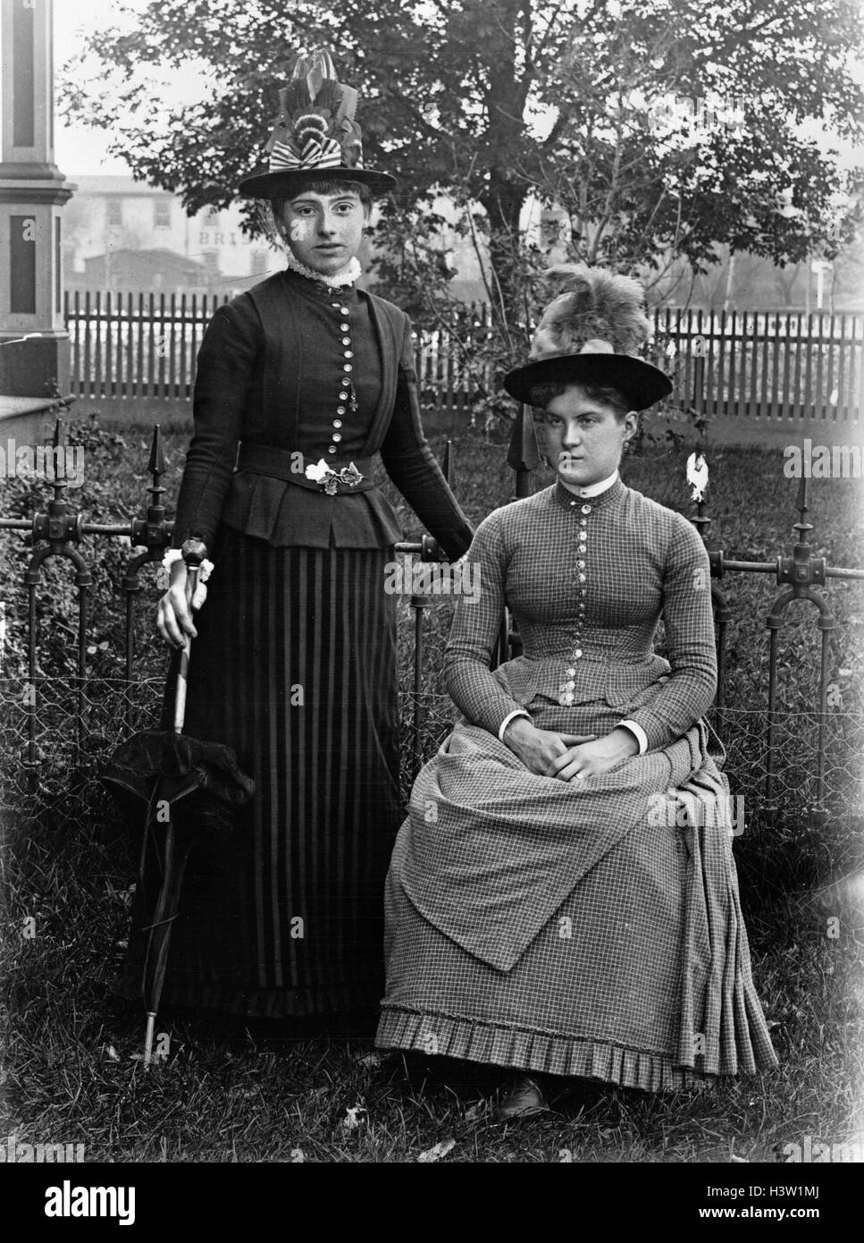 1880s 1890s PORTRAIT TWO WOMEN IN STYLISH CLOTHES WEARING HATS IN FRONT LAWN POSED LOOKING AT CAMERA Stock Photo