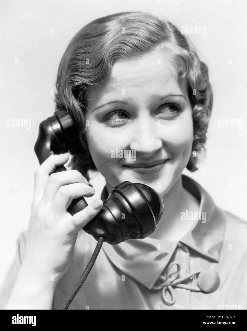 1930s SMILING WOMAN TALKING ON TELEPHONE Stock Photo