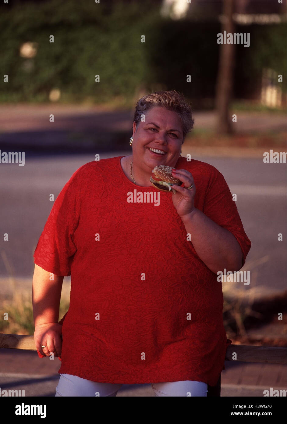 Woman, thickly, eat, hamburgers, overweight, fatly, adiposity, Almost Food, nutrition, unhealthily, food, lean, fence, outside Stock Photo