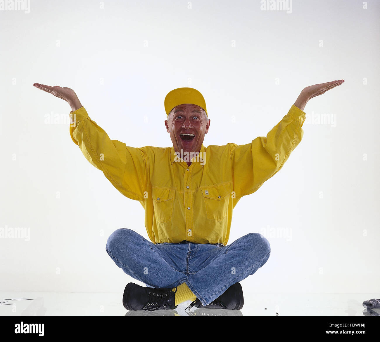 Senior, sign cap, laugh, sit, present gesture, man, headgear, cross legged, facial play, happy, hands lift, lift, joy, cheering, enthusiasm, presentation, studio, cut outs, Stock Photo