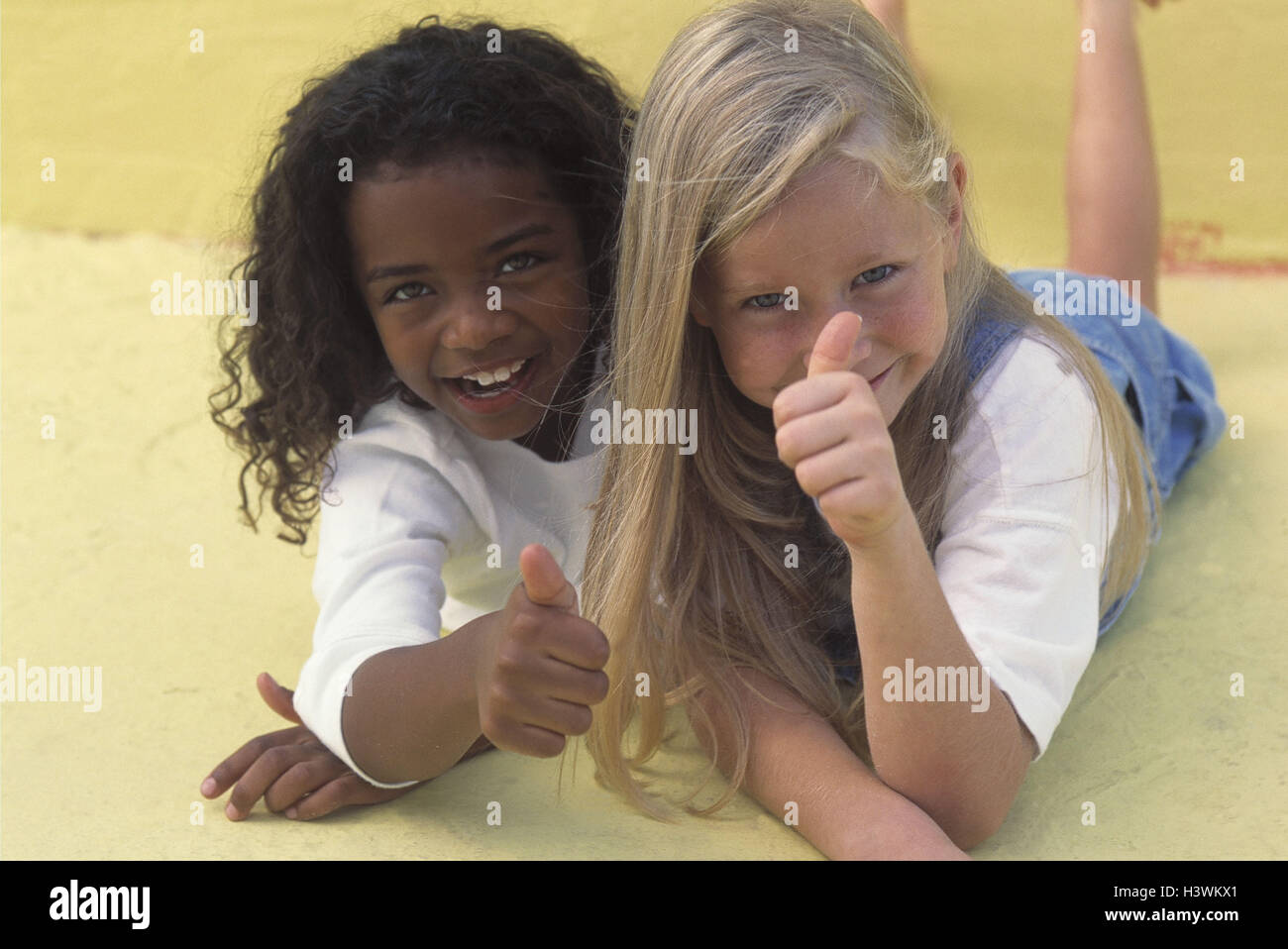 Girls, different colour of skin, lie, play gesture, 'pollex high' friends, friendship, friends, nationality, differently, non-whites, whiteness, children, blond, dark-haired, childhood, fun, cheerfulness, satisfaction, happy, cohesion, inside Stock Photo
