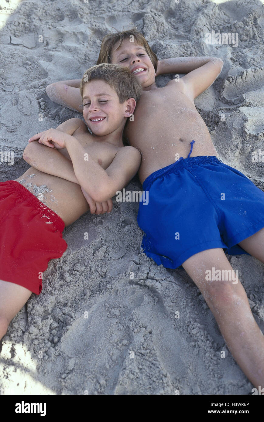 Sandy beach, boy, shade, lie, rest, very close, outside, beach, Sand, vacation, holidays, leisure time, childhood, friends, siblings, brothers, children, 7 + 10 years, happy, rest, take it easy, relaxing, recreation, swimming trunks, swimwear Stock Photo