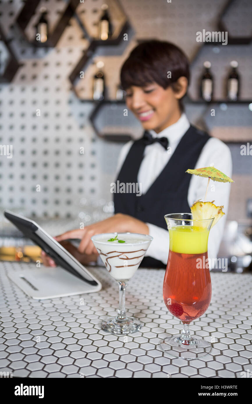 Waitress using digital tablet with glass of cocktail in bar counter Stock Photo