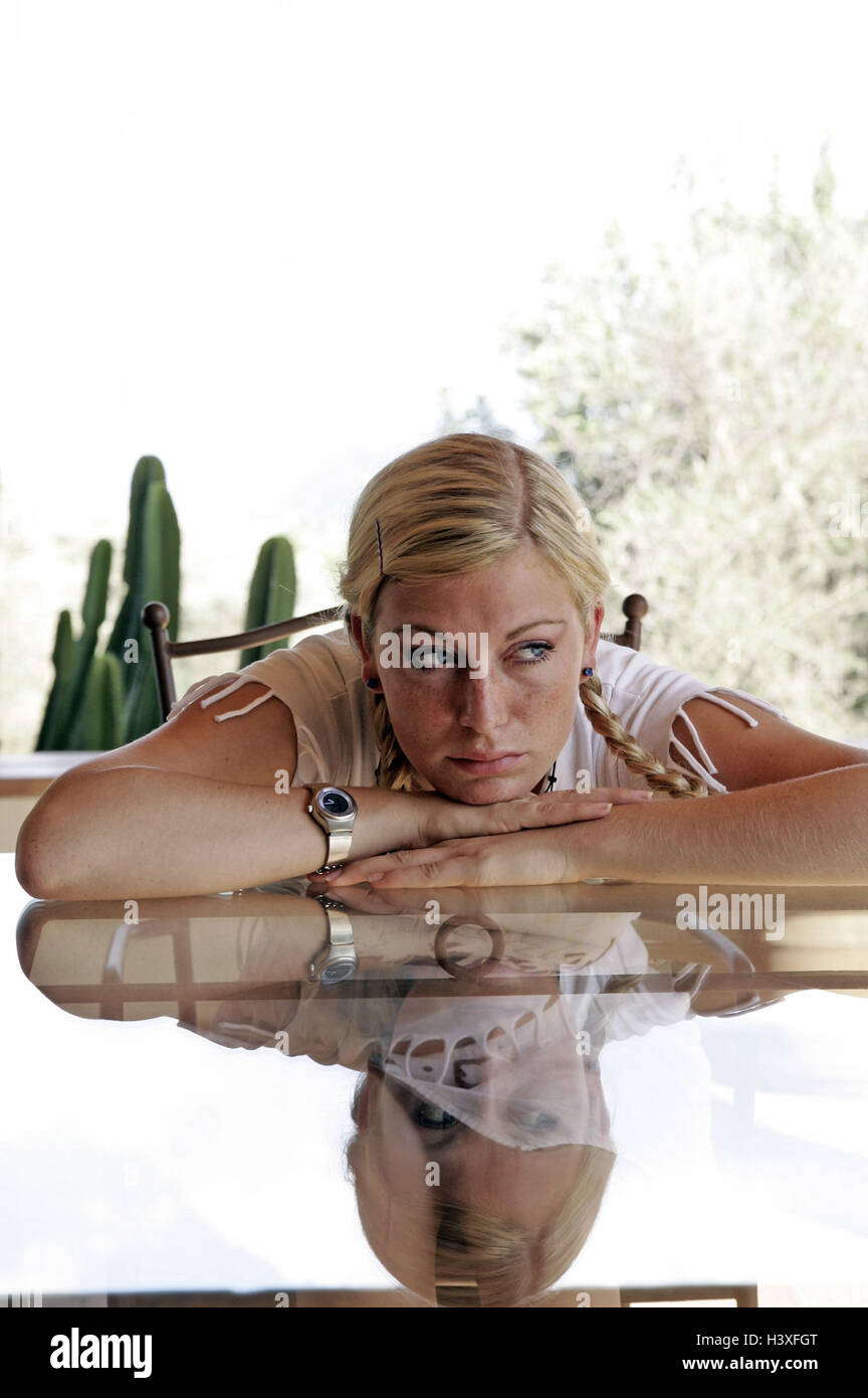 Woman, young, blond, braids, Glastisch,  resting, seriously, knocked down,  Look on the side 24 years, 20-30 years, emotion, sorrowfully, secluded, depressed, problem, sorrow, longing, lovesickness, worries, disappointment, sorrow, table, glass plate, reflection, Stock Photo