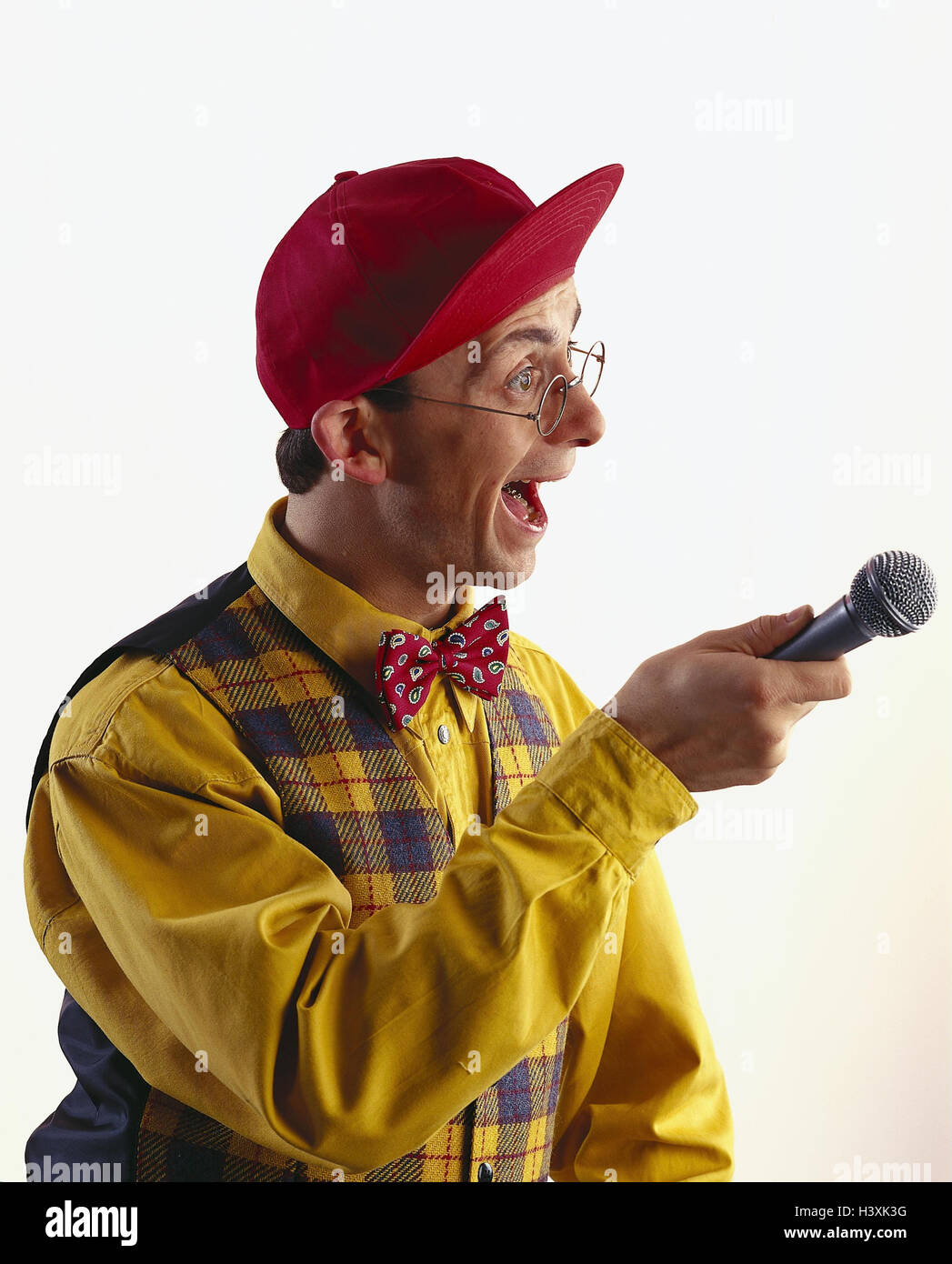 Man, glasses, baseball cap, gesture, microphone, interview reporter, headgear, clothes, shrill, bundle, yellow, red, facial play, enthusiasm, enthusiasm, surprises, press work, side view, studio, cut out Stock Photo