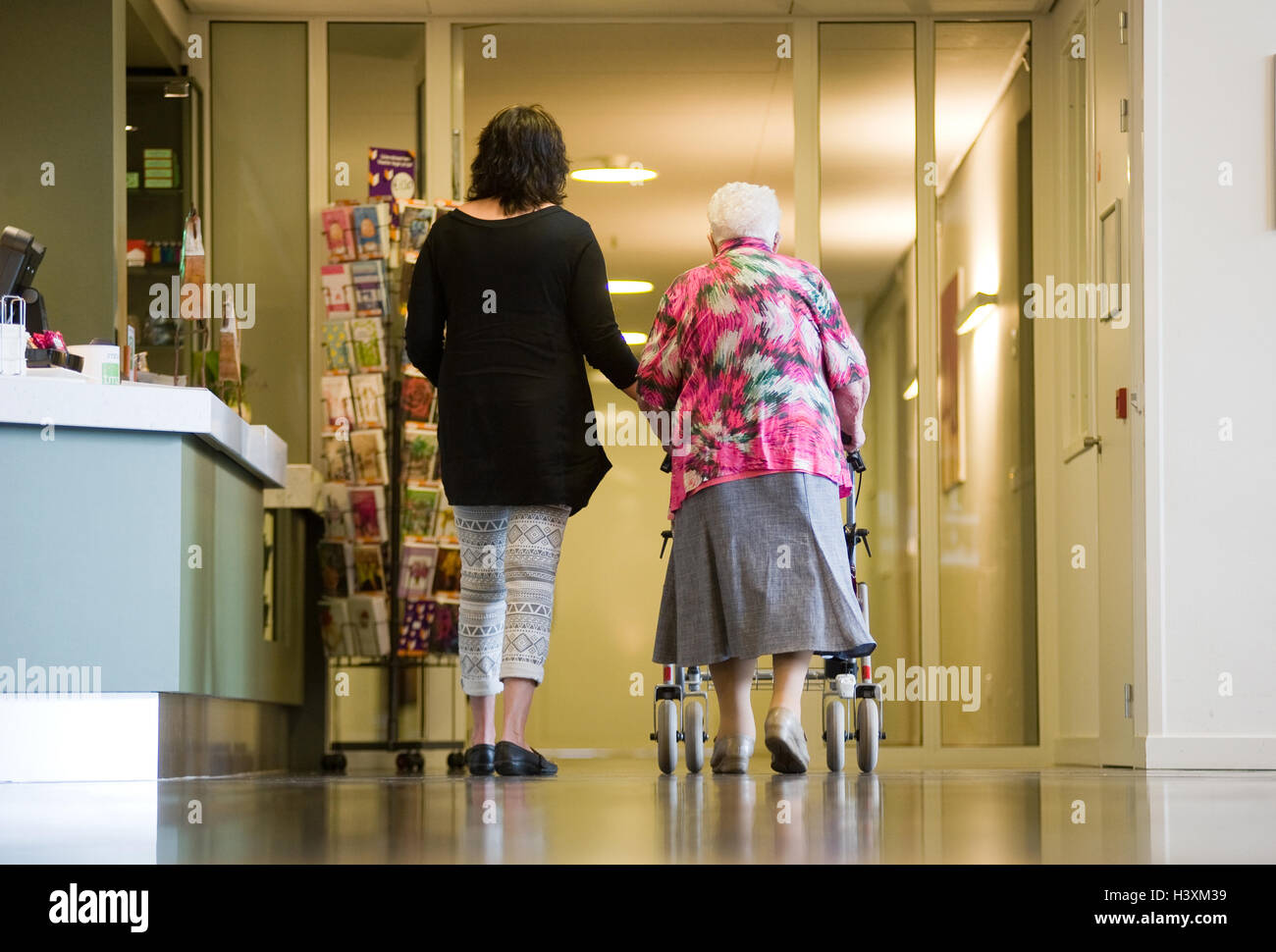 ALMELO, THE NETHERLANDS - JUNE 15, 2016: A woman is assisting an elderly woman with a rollator in an elderly home. Stock Photo