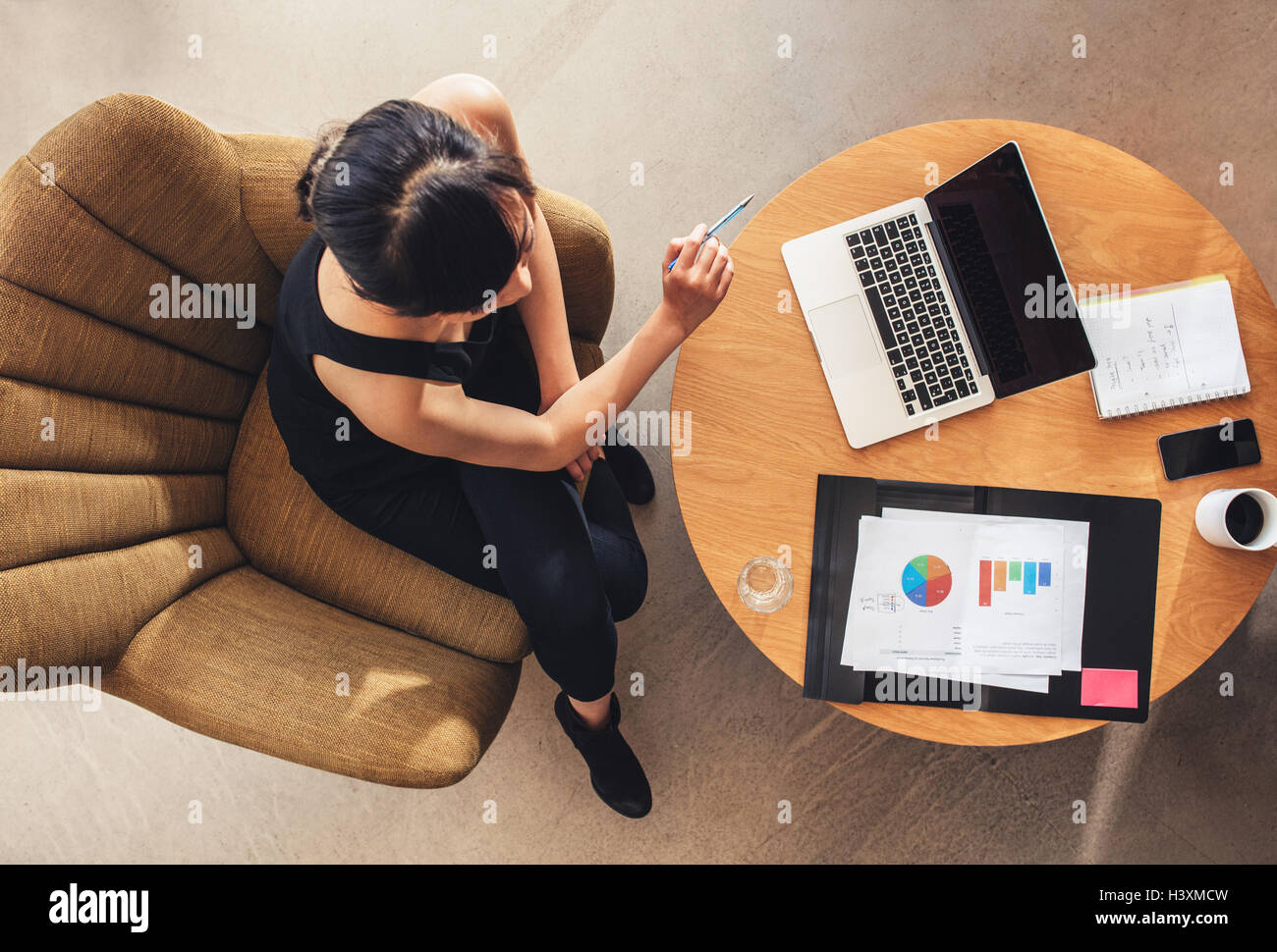 Top view of young woman sitting at table with laptop and charts. businesswoman working on new business project in office lobby. Stock Photo