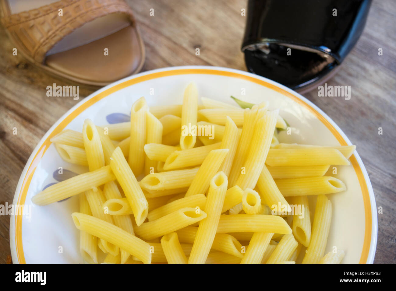flat lay of a dish of pennette pasta near woman shoes Stock Photo