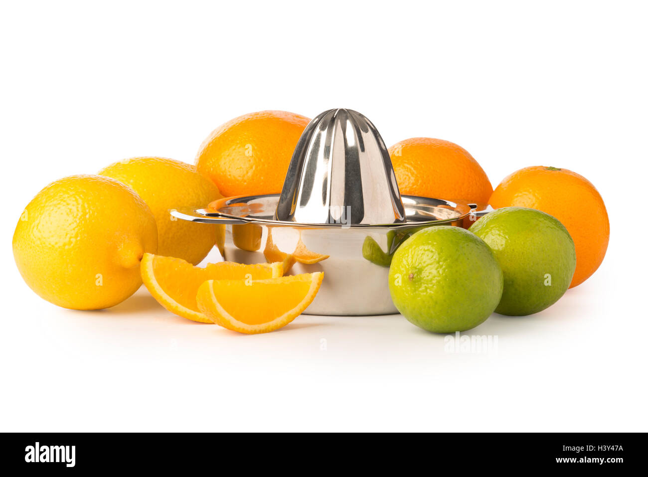Cutout of a stainless steel orange or citrus hand juicer surrounded by whole lemons, oranges, lime, and a pair of orange slices. Stock Photo