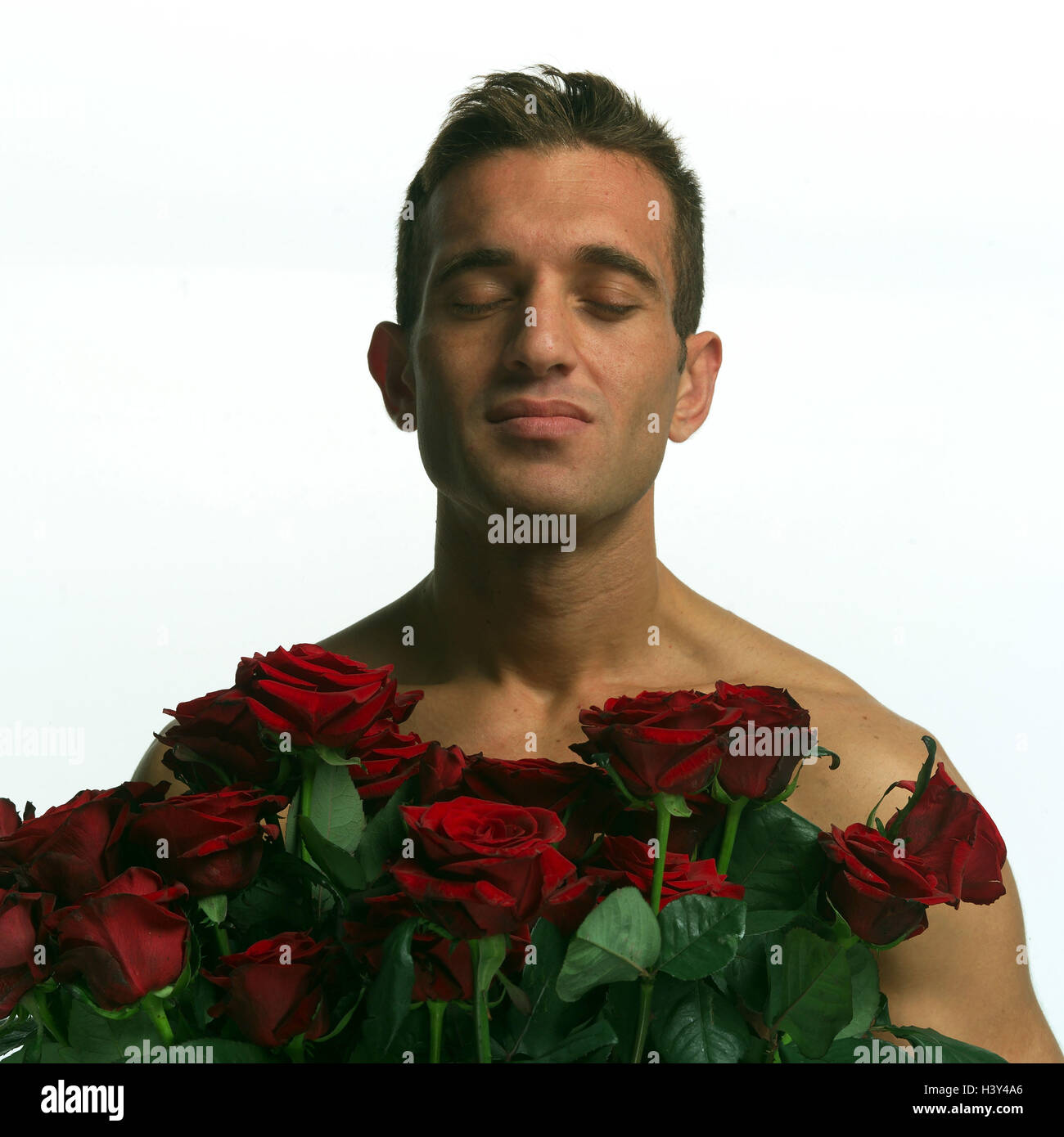 Man, young, free upper part of the body, bunch of roses, portrait, model released, very close, studio, Knight of the Rose, eyes closed roses, red, flowers, give, sign of love, attention, imaginatively, 'let flowers speaking', enjoy, odour, smell, smell, inhale, fallen in love, love Stock Photo