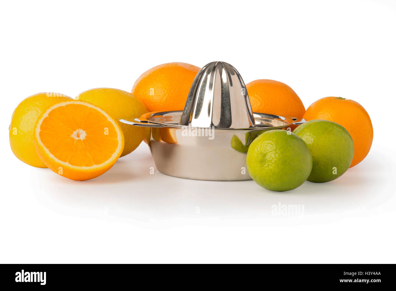 Cutout of a stainless steel orange or citrus hand juicer surrounded by whole lemons, oranges, lime, and half an orange. Stock Photo
