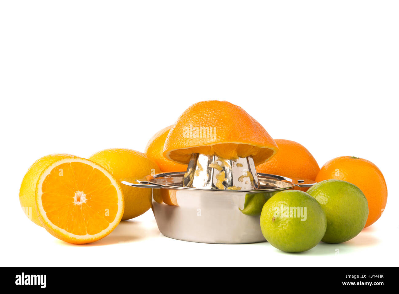 Half an orange on stainless steel orange or citrus hand juicer surrounded by whole lemons, oranges, and lime Stock Photo