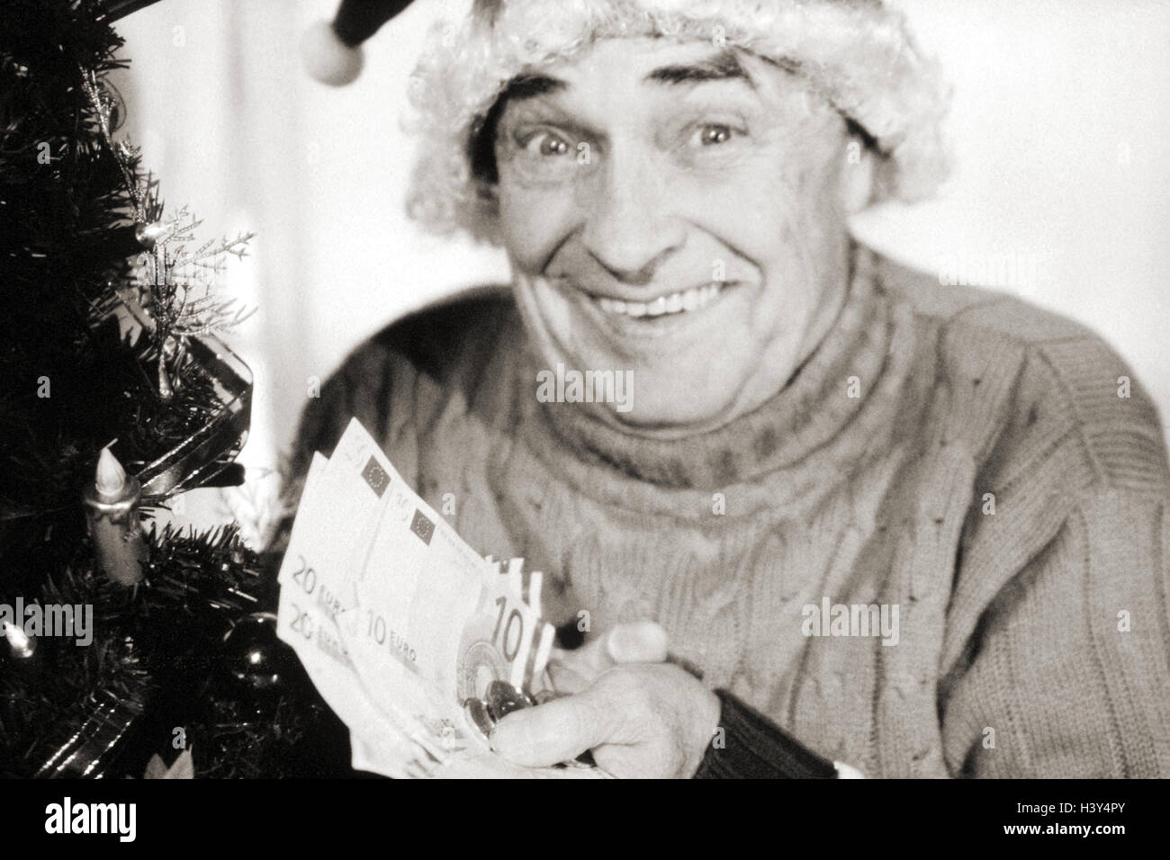 Christmas, senior, Santa's hat, hand, euro, bank notes, coins, b/w, inside, Christmas tree, Christmas tree, for Christmas, man, old, gesture, joy, happy, Europe, currency, single currency, banknotes, euronotes, money, gift money, present Stock Photo