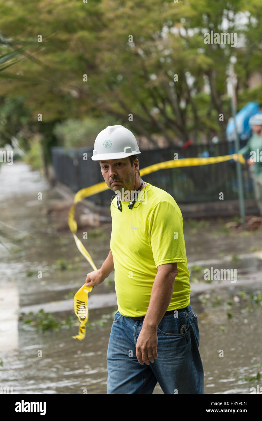 A city worker pulls caution tape across Meeting Street closed by flood waters in historic downtown after Hurricane Matthew passed through causing flooding and light damage to the area October 8, 2016 in Charleston, South Carolina. The hurricane made landfall near Charleston as a Category 2 storm but quickly diminished as it moved north. Stock Photo