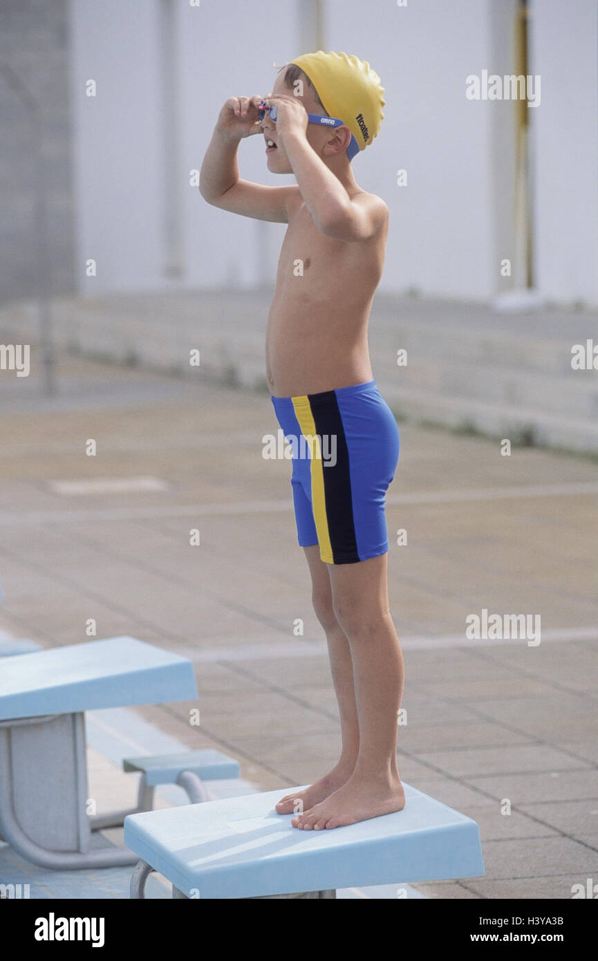 Swimming-pool, cymbal margin, starting block, boy, swimwear, swimming glasses, straighten outside, child, 9 years, bathing cap, swimming trunks, swimming pool, leisure time, holidays, vacation, childhood, hobby, event, start line-up, touch down, training, swimming training, train, at the side Stock Photo