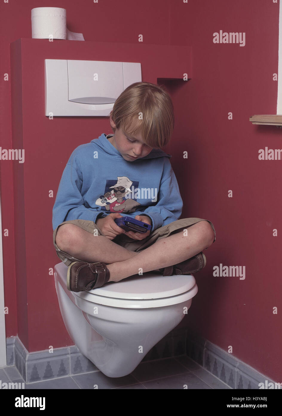 Toilet, boy, Gameboy, play, inside, bath, bathroom, child, 7 years, leisure time, childhood, game, gambling addiction, pouch computer, computer game, dissatisfied, discontent, concentrates, concentration Stock Photo