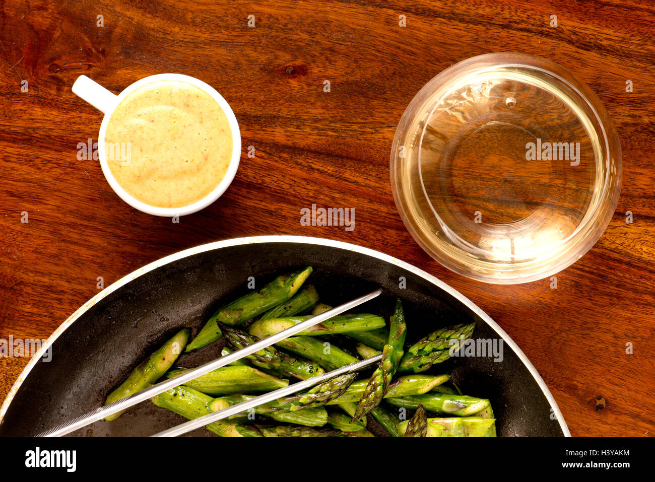 Fried green asparagus in pan. Served with sauce and white wine. Stock Photo