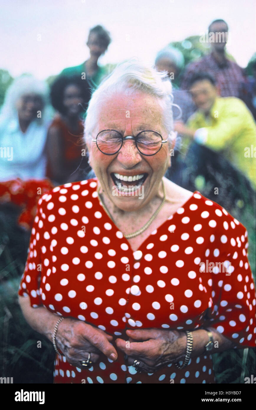 Senior, laugh, fun, humor, half portrait, senior citizens, old person, woman, old, glasses, eyes closed, tuning, facial play, expression, happily, cheerfully, funnily, warmly, amuses, funnily, amusement, emotion, warmly, amuses, humorously, joke, summer dress, dots, red-white, summer, outside, background, group Stock Photo