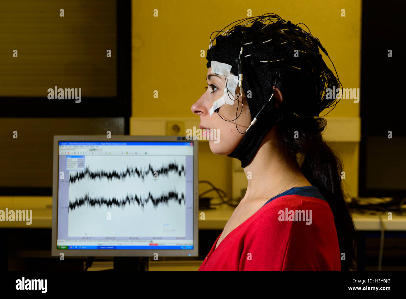 Person undergoing an electroencephalogram with an EEG cap to scan her brain's electrical activity Stock Photo