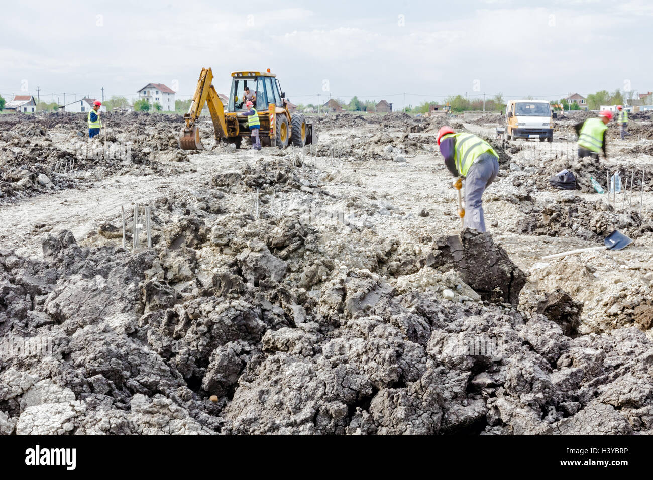 Zrenjanin, Vojvodina, Serbia - June 14, 2015: Backhoe tractor is working on a construction site. Group of workers with shovels a Stock Photo