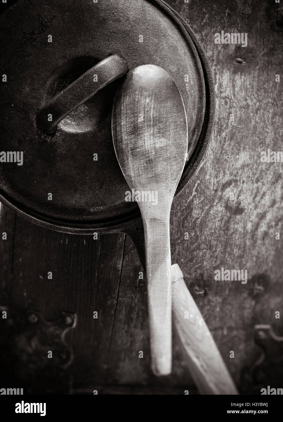 Vintage pot and wood ladle, top view. Old metal pan with lid on wooden kitchen table. Stock Photo