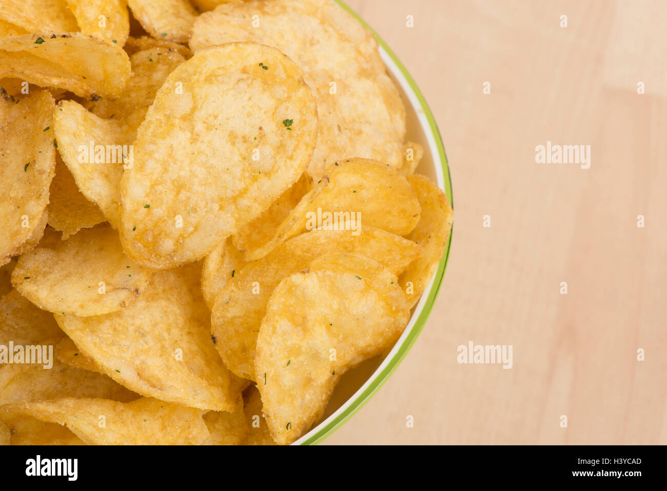 Potato chips in bowl on table. Close up of salty and fat snack. Unhealthy eating. Stock Photo