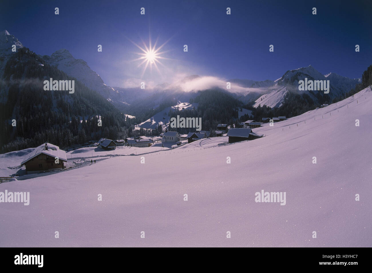 Austria, small Walsertal, Baad, 1244 m, local view, church, back light, winter, Europe, Vorarlberg, Kleinwalsertal, district the parish Mittelberg, village, place, houses, residential houses, mountain landscape, mountains, Aries's stone, 2533 m, snow, sea Stock Photo