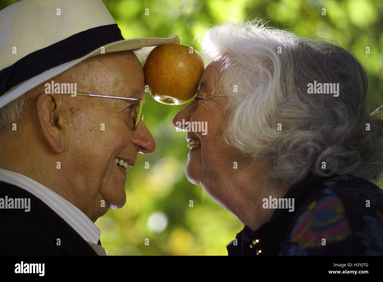 Senior couple, happy, eye contact, forehead, apple, get caught, tread couple, senior citizens, partnership, Before, respect, happy, falls in love, love, affection, together, fun, joy life, gambles away, care, headgear, glasses, wearers glasses, park, garden, outside Stock Photo
