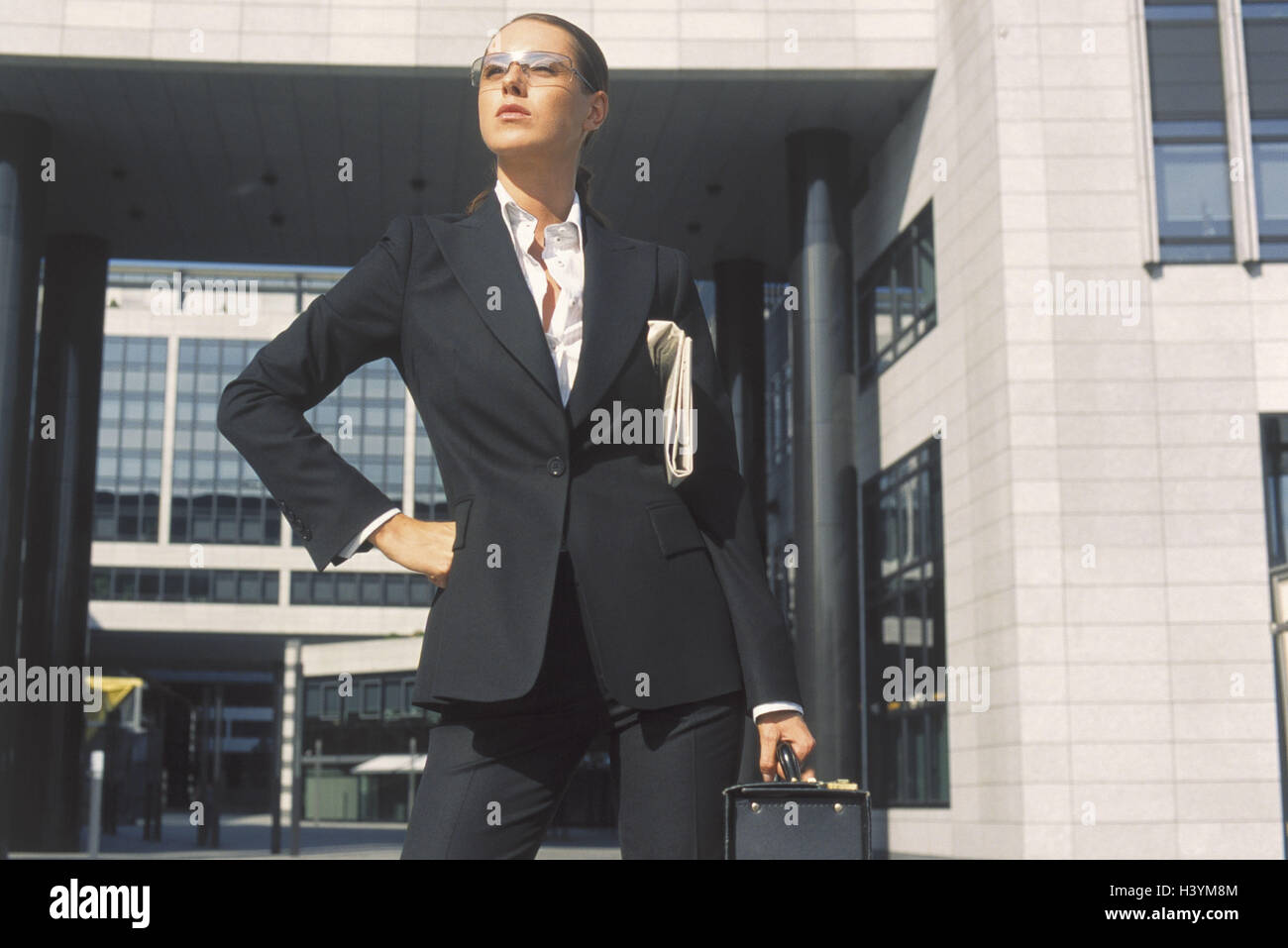Businesswoman, challenging, half portrait, office buildings, occupation, business, woman, suit, career woman, manager, glasses, stand, decided, stand self-confidently, dominant, ambitiously, energetically, energetically, seriously, briefcase, briefcase, n Stock Photo