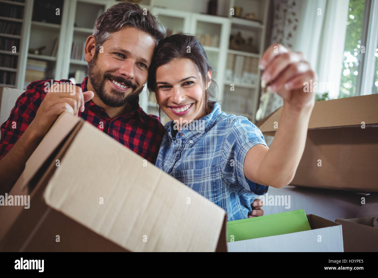 Smiling couple holding keys in their new house Stock Photo - Alamy