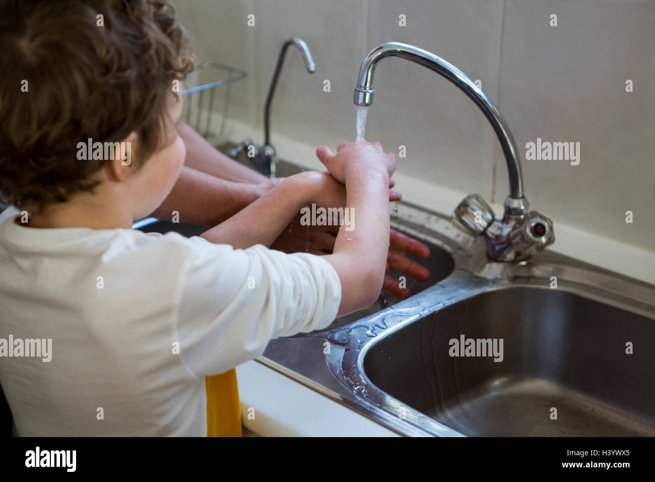 Father and son washing hands in the kitchen sink Stock Photo Alamy
