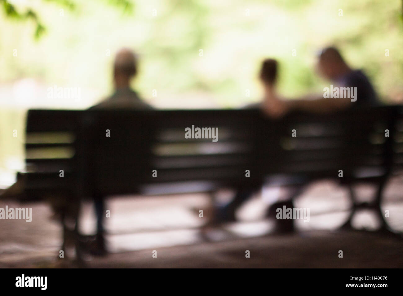 Defocused image of people sitting on bench at park Stock Photo