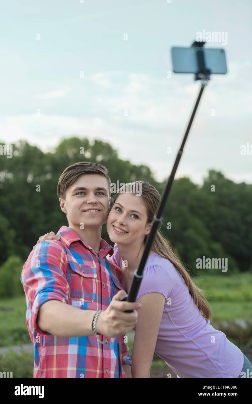Happy young couple taking selfie through monopod at park Stock Photo ...