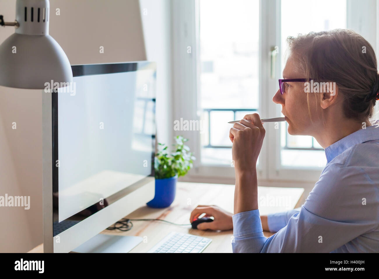 Young business woman thinking of project in front of computer in modern office interior Stock Photo