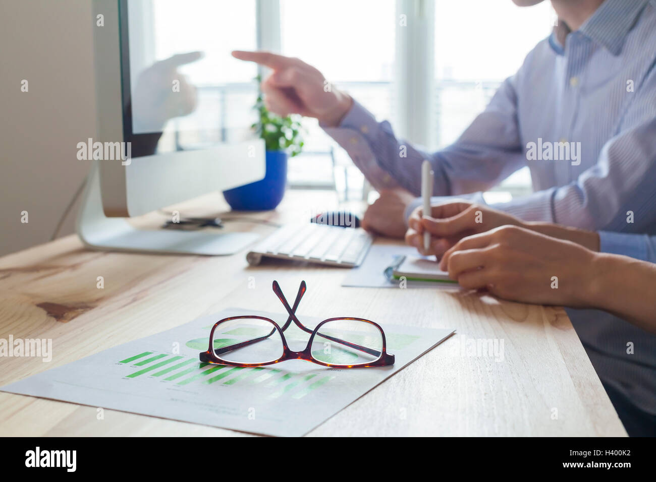 Meeting of business people in co-working office, one person teaching the other one, close-up on glasses Stock Photo